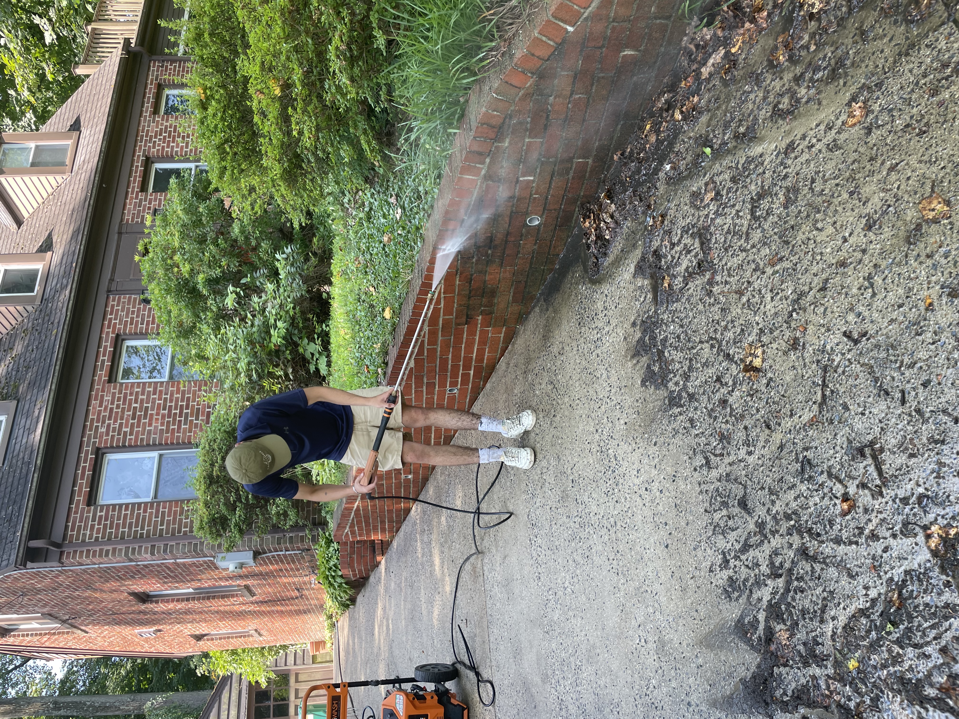 NW Pressure Washers cleaning a driveway in front of a brick home